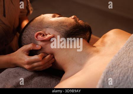 Uomo che riceve un massaggio professionale al collo nel salone spa, concetto di massaggio Foto Stock