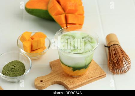 Primo piano del latte Matcha di mango Iced fatto in casa sul tavolo bianco Foto Stock