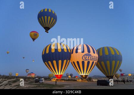 Diverse mongolfiere colorate si innalzano nel cielo mattutino su un vasto paesaggio, il Parco Nazionale di Goereme, il Parco Tarihi Milli di Goereme e la Provincia di Nevsehir Foto Stock