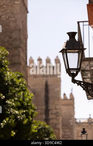 Una lampada da strada in ferro battuto si erge nel paesaggio storico della città di Siviglia, Andalusia, Spagna. Foto Stock