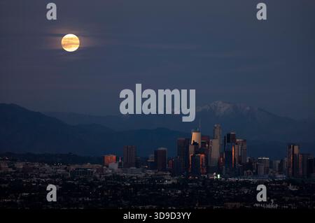 Los Angeles, California, Stati Uniti. 4 dicembre 2025. L'ultima super luna dell'anno, la "Cold Supermoon", sorge sulle montagne innevate, dietro lo skyline del centro di Los Angeles, si vede dall'area ricreativa statale Kenneth Hahn il giovedì a Los Angeles. (Credit Image: © Ringo Chiu/ZUMA Press Wire) SOLO PER USO EDITORIALE! Non per USO commerciale! Foto Stock