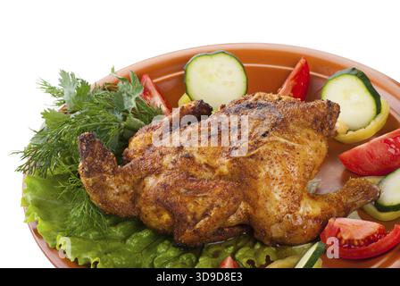 Pollo intero fresco alla griglia con cetriolo, pomodori crudi sul piatto con lattuga isolata su fondo bianco Foto Stock