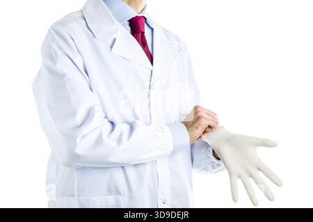 Maschio caucasico medico vestito in camice bianco, blu camicia e cravatta rossa è monouso da indossare dei guanti di protezione in lattice Foto Stock