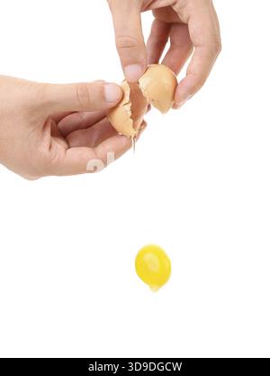 Primo piano dell'uovo rotto in mano, tuorlo che cade Foto Stock