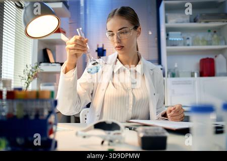 Giovane donna caucasica adulta che conduce esperimenti chimici in laboratorio Foto Stock
