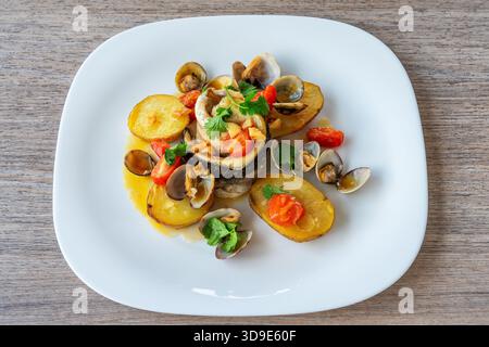 Delizioso piatto a base di pesce con tenero filetto di pesce, patate arrosto e verdure fresche, splendidamente disposto su un piatto bianco per la cucina Foto Stock
