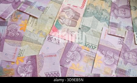 Banconote in rupia indonesiana sparsi in vari tagli che mostrano il vivace design della valuta, evidenziando i dettagli del popolo e del cultur Foto Stock