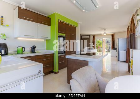 Cucina moderna con elettrodomestici eleganti, arredi luminosi e ampio accesso al soggiorno. Foto Stock