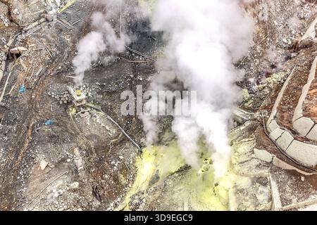 Fumarole e un sistema di monitoraggio del vapore nel cratere di Owakudani, Hakone, Kanagawa, Giappone. Fumo denso si alza dal campo di fumarole giallo zolfo; a sinistra dell'immagine si trova la stazione di monitoraggio, e a destra ci sono elementi in cemento dei lavori di stabilizzazione del pendio. L'attività vulcanica attiva di Owakudani è legata alla camera magmatica sotto il sistema vulcanico di Hakone Foto Stock