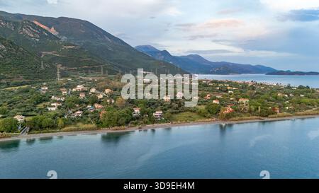Vista aerea con droni di Marathias, un villaggio costiero della Grecia centrale, che mostra la costa del Golfo di Corinto, il mare azzurro cristallino e le case tradizionali. Foto Stock