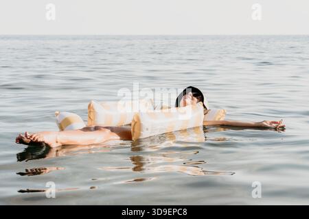 Donna che galleggia sull'acqua salata del Mar morto Foto Stock