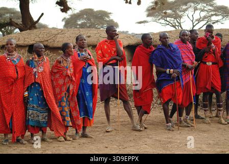 Masai Mara, Kenia - 23 agosto 2010: Gruppo di uomini e donne africani non identificati della tribù Masai in abiti di cotone multicolore e gioielli in perline in a. Foto Stock