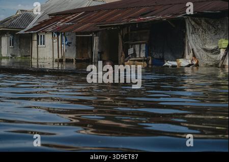 Yenagoa, Nigeria - 8 ottobre 2022: Vista di un bambino in mezzo a un'area residenziale allagata, che riflette la cupa realtà delle vite sfollate in acque torbide Foto Stock
