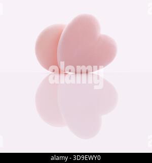 Soffice puff rosa a forma di cuore, adatto per l'applicazione di polvere, fondazioni o la rimozione del trucco. I prodotti di bellezza sono isolati su un riflesso lucido Foto Stock