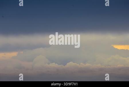 Un cielo sereno riflette incantevoli tonalità del tramonto, colorando delicatamente le nuvole e offrendo un momento tranquillo e rilassante di delicata luce serale. Foto Stock