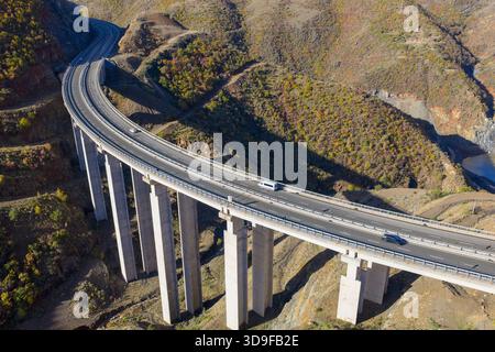 Veduta sopraelevata del viadotto autostradale A1 che attraversa il ripido e accidentato terreno di Kolsh nella contea di Kukës, circondato da colline color autunno e dal dr Foto Stock