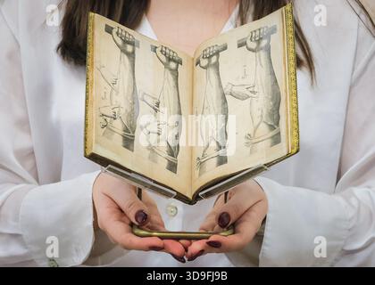 Londra, Regno Unito. 5 dicembre 2025. Lo staff di Christie con la prima edizione di Harvey William che annunciava la circolazione del sangue. Copia di Letherland-Osler. Stima: £800.000-1.200.000. La promozione Christie's Valuable Books & Manuscripts, parte della Classic Week, si terrà il 10 dicembre 2025. Crediti: Imageplotter/Alamy Live News Foto Stock