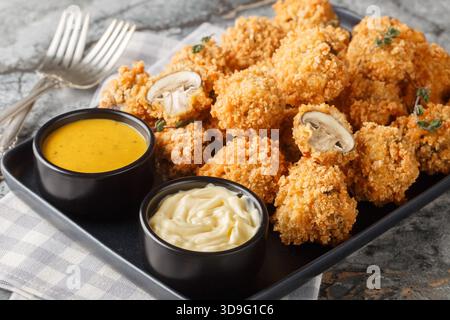 Primi piani di funghi impanati all'aglio croccanti in un piatto sul tavolo. Orizzontale Foto Stock