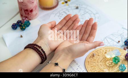 Mani che reggono una serie di pietre rune, con carte astrologiche sullo sfondo. Dire la fortuna. Foto Stock