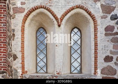 Finestre in vetro incorniciate in legno su un vecchio edificio decorativo in pietra e mattoni. Foto Stock