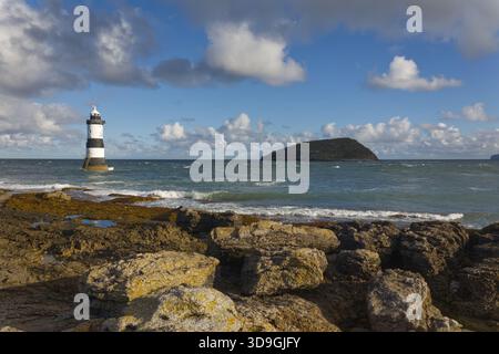 Faro di Trwyn Du, noto anche come faro di Penmon, a Penmon Point sulla costa orientale di Anglesey, Galles del Nord, con Puffin Island (Ynys Seiriol) Foto Stock