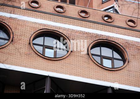 Edificio moderno caratterizzato da finestre rotonde contro la facciata in mattoni, che mette in risalto il design Foto Stock