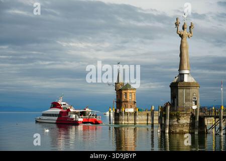 Un traghetto passeggeri arriva al panoramico porto di Costanza sul lago di Costanza (Bodensee) con la statua di Imperia e il faro storico sul retro Foto Stock