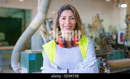 Lavoratrice industriale che sorride nell'officina di fabbrica Foto Stock