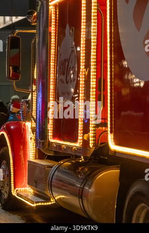 La cabina illuminata di un camion rosso brilla di luci tra i visitatori dell'evento natalizio della città. Austria, Vienna, 12 dicembre 2024 Foto Stock
