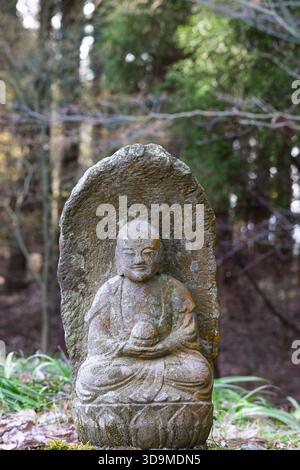 Piccola placca scultorea del Buddha Gautama ricoperta di licheni, tempio Saigandenji nel piccolo villaggio di Aso Kumamoto, in Giappone Foto Stock