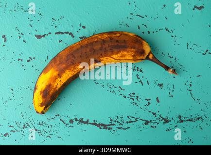 Vista dall'alto di una banana troppo matura su un ripiano a chiocciola verde e nero. Foto Stock
