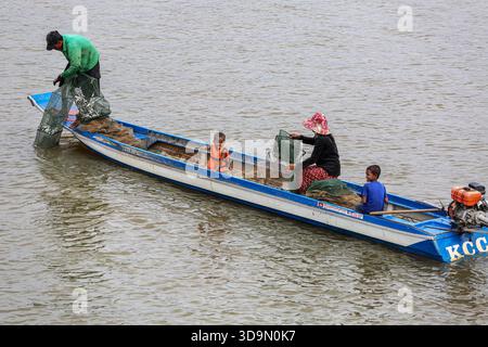 Fiume Tonle SAP, Cambogia. 6 dicembre 2025. I pescatori cambogiani recuperano le loro trappole quadrate di pesce dalle tradizionali barche in legno sul fiume Tonle SAP, approfittando della migrazione stagionale del pesce mentre il lago continua a drenare verso il fiume Mekong dopo l'inversione annuale del flusso all'inizio di ottobre. Durante questo periodo di deflusso, un gran numero di piccole specie di acqua dolce si spostano a valle in scuole dense. Questo raro fenomeno idrologico crea le condizioni ideali per le comunità di pescatori locali che si affidano pesantemente a questa stagione per la raccolta di pesci d'acqua dolce. Crediti: Kevin Izorce/Alamy Live News Foto Stock