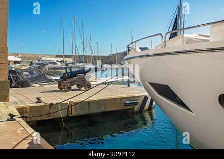 Cannone antico su una carrozza di legno e la prua di un moderno yacht bianco di lusso sullo sfondo del blu del Mar Mediterraneo. Foto Stock
