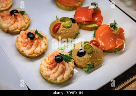 Panini a vista Belegte Brotli con gamberetti, insalata di tonno e salmone affumicato su un piatto bianco da portata in vendita in una panetteria di Zurigo, Svizzera Foto Stock