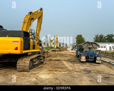 Escavatori e camion in terra battuta su una strada della città in una scena di costruzione stradale in cui una strada della città è in fase di ricostruzione. Foto Stock