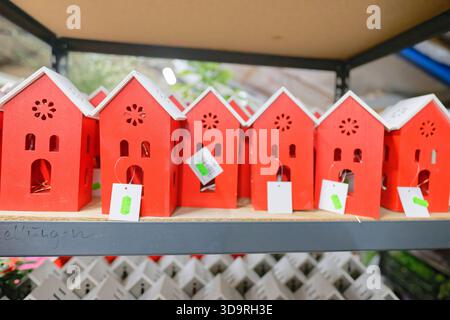 Uno scaffale mostra piccole case di legno rosse con tetti bianchi. Le case sono compatte e hanno un prezzo di sei cinquanta euro ciascuno nel display. Foto Stock