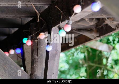 Un vecchio rifugio in legno è coperto da spesse ragnatele bianche. Le colorate lampadine rotonde sono appese alle grandi unghie del soffitto, creando un ambiente rustico e sli Foto Stock