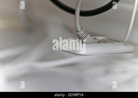 Un coperchio rotondo in plastica è posizionato a filo su un piano portapaziente bianco, i cavi cadono ordinatamente attraverso l'apertura e scompaiono sotto, mantenendo l'area di lavoro pulita, ordinata, A. Foto Stock