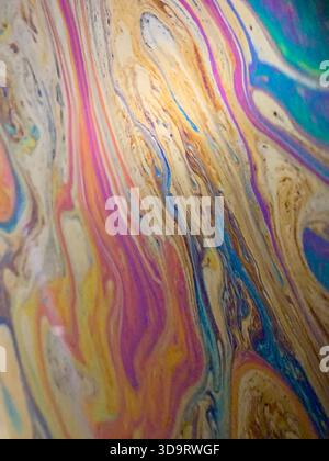 Un vivace motivo astratto caratterizzato da colori vorticosi di viola, oro e blu, che ricordano un effetto marmorizzato. Le linee fluide e fluide creano un senso Foto Stock