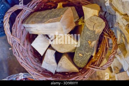 Un cestino pieno di vari pezzi di legna da ardere, tra cui tronchi e legna tagliata in diverse forme e dimensioni, sistemato in modo ordinato. Foto Stock