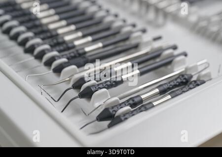 Vista ravvicinata degli strumenti dentali ordinatamente disposti in un vassoio Gli strumenti includono vari tipi di esploratori odontoiatrici e scaler, che mostrano il loro shi Foto Stock