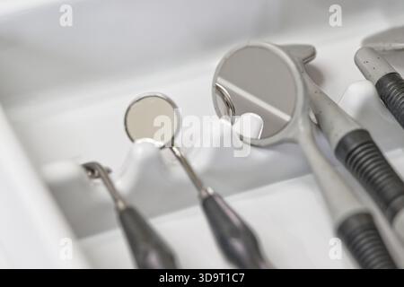 Primo piano di strumenti odontoiatrici, tra cui specchi ed esploratori, disposti ordinatamente in un vassoio Foto Stock