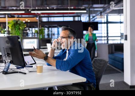 Colleghi diversi in ufficio, uomo che parla con lo smartphone, donna in blazer che cammina, copia spazio Foto Stock