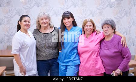 Il personale della casa di cura e le donne anziane sorridono insieme Foto Stock