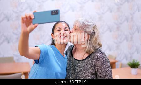 Nipote che si fa selfie con la nonna in casa di riposo Foto Stock