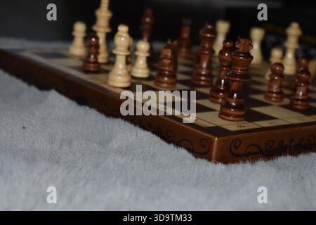 Scacchi bianchi e neri su una scacchiera di legno Foto Stock