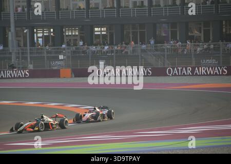 Due auto da corsa gareggiano a stretto contatto sul tracciato del Gran Premio del Qatar, mentre i tifosi guardano dagli stand sullo sfondo. Foto Stock