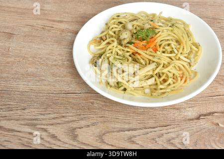 spaghetti saltati speziati con capesante in salsa all'aglio e burro e condimento dell'uovo di gamberi sul piatto Foto Stock