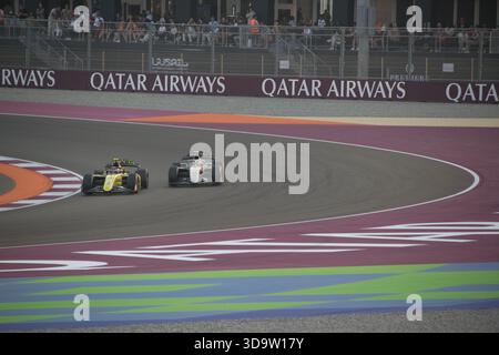 Due auto da corsa gareggiano a stretto contatto sul tracciato del Gran Premio del Qatar con i tifosi che guardano dagli stand nel 2025 Foto Stock