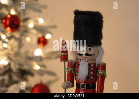 Statua classica dello schiaccianoci in un accogliente ambiente natalizio con un albero di Natale illuminato dietro di essa. Foto Stock